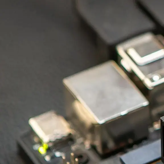 The ports and pin headers of an edge AI compute board mounted on a base plate, with cables attached.